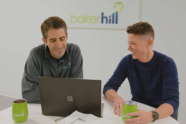 Two Baker Hill employees working together with a laptop at a table.